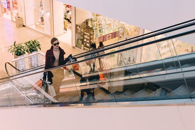 Woman with shopping bags using an escalator, denoting the everyday scenarios where premises liability issues, handled by Kevin R. Hansen's law firm, can arise