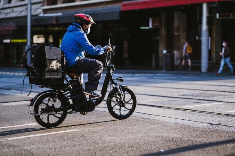 Motociclista con casco, acercándose con precaución a un cruce de vías de tren en una metrópoli, encarnando el enfoque prudente defendido por Kevin R. Hansen, Abogado de Accidentes de E-Bike en Las Vegas.