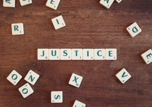 Scrabble letters spelling 'Justice' on a table, symbolizing the commitment of our Law Office to legal fairness.