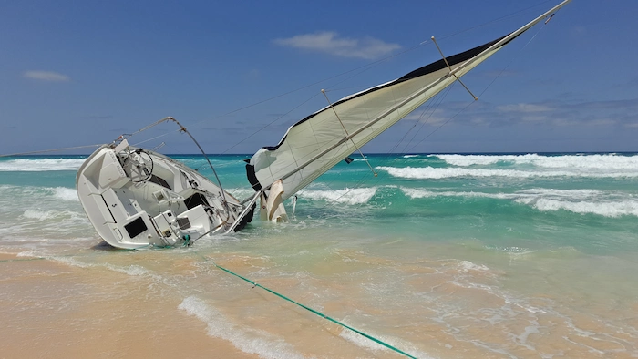 Sailboat caught sideways in the surf breakers - representation of a boating accident scenario.