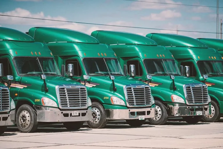 Large green semi trucks parked side by side