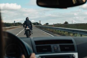 A motorcycle rider being followed too closely by a car driver.